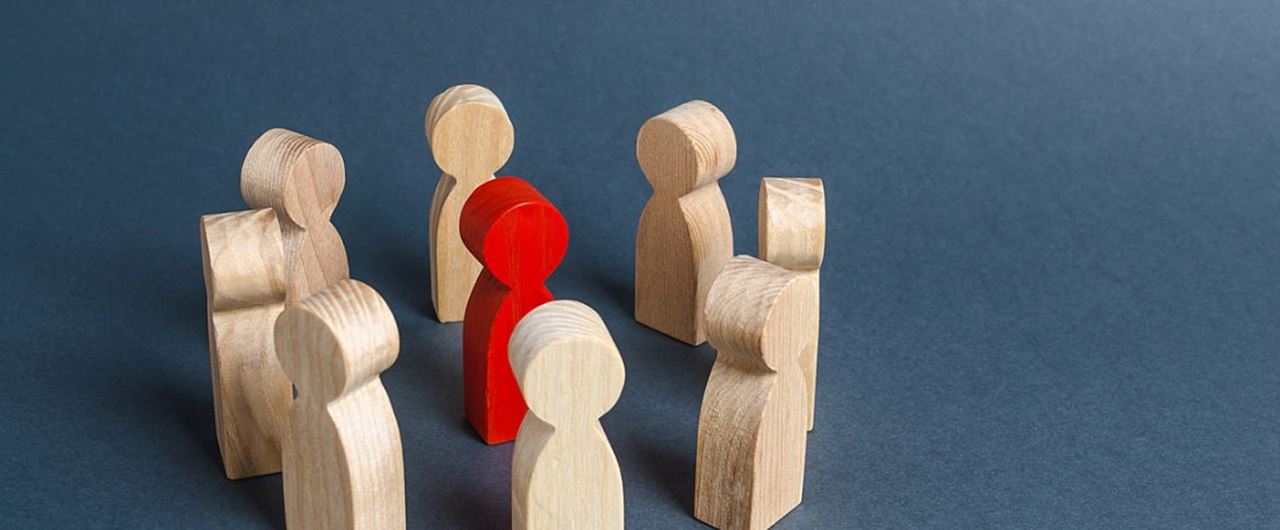 Figurines en bois disposées en cercle autour d'une figurine en bois rouge