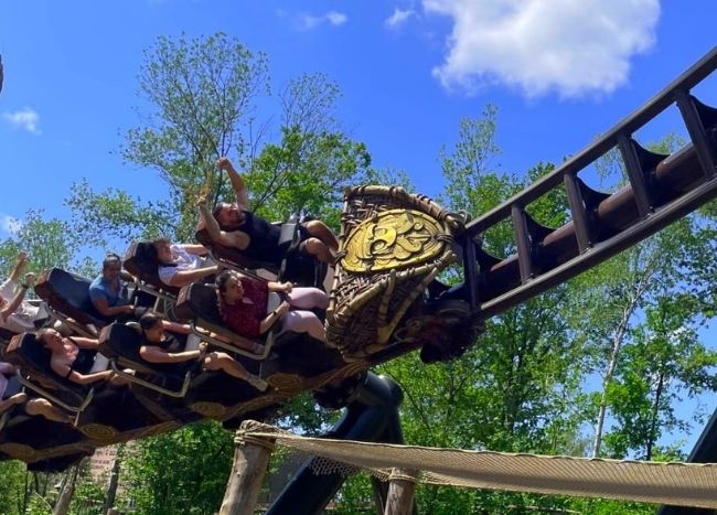 Visiteurs profitant d’une attraction de montagne russe du Parc Astérix avec un décor thématique en plein air