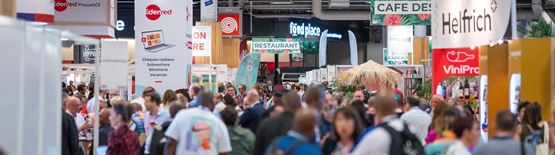 Photographie d'une foule avec plusieurs pancartes au nom des différentes entreprises qui exposent sur le salon