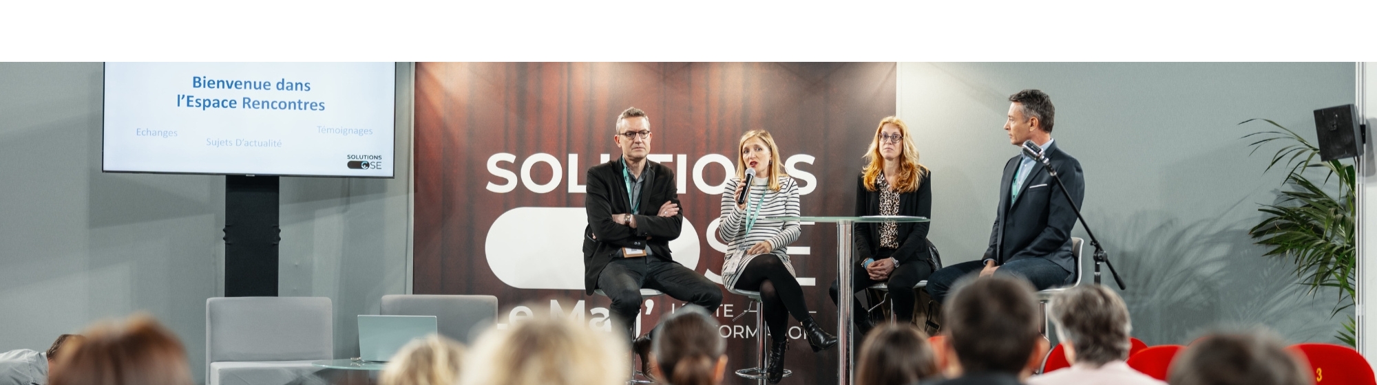 Table ronde lors d’un salon professionnel avec plusieurs intervenants sur scène devant un public.