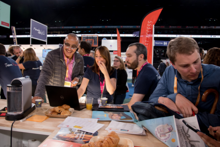 Exposants discutant autour d'une table avec des ordinateurs et une machine à café