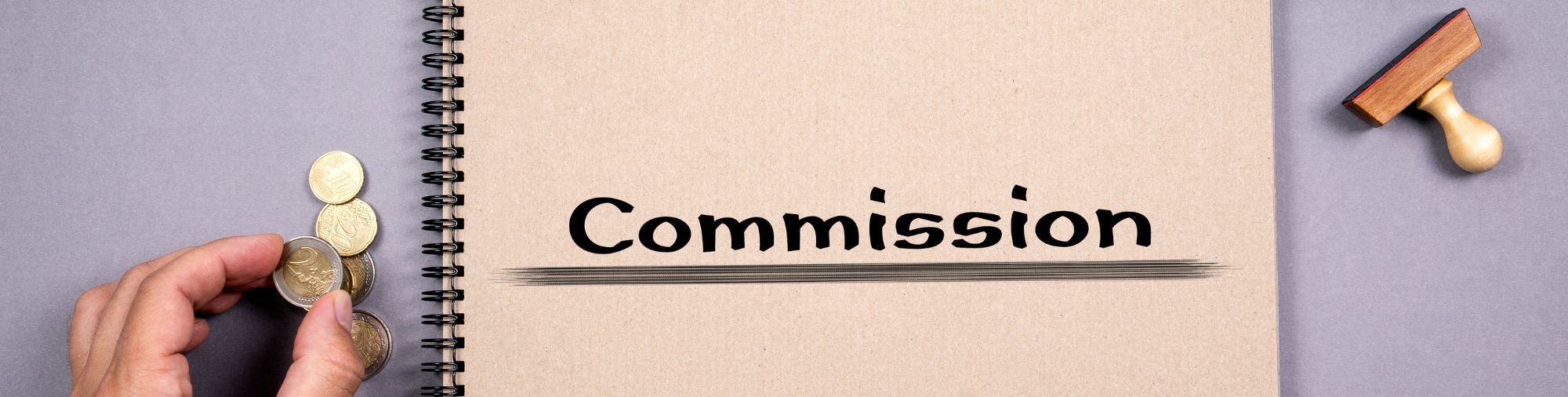 Carnet ouvert avec le mot Commission entouré de pièces et de fournitures de bureau