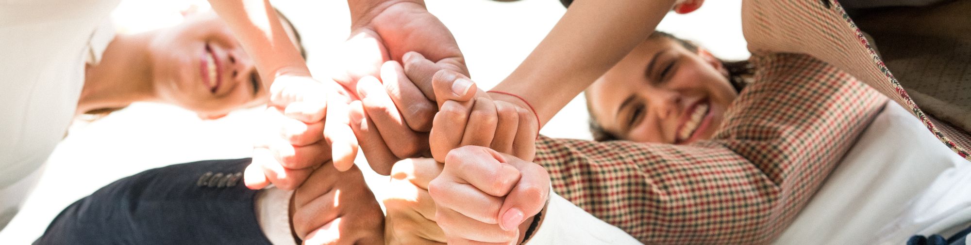 Groupe de professionnels réunissant leurs mains au centre pour symboliser l’esprit d’équipe et la collaboration