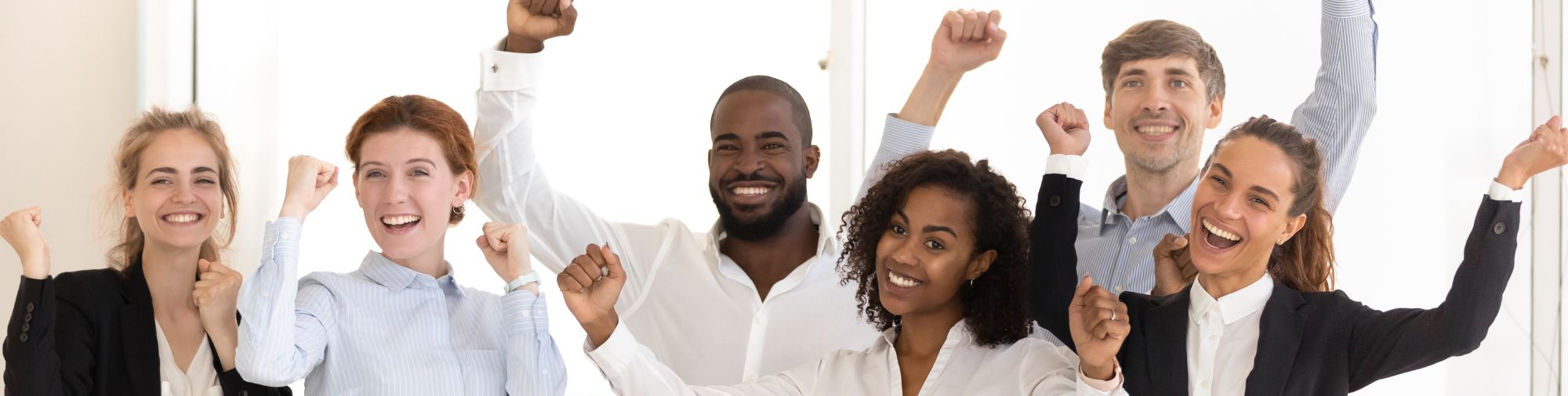 Équipe de salariés souriants levant les bras pour célébrer une réussite
