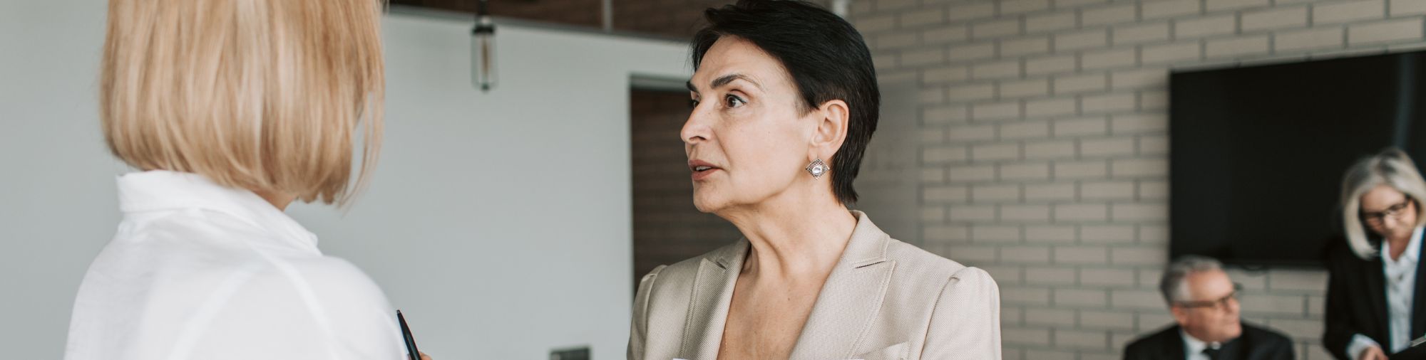 Négociation d’un protocole préélectoral Deux femmes en discussion sérieuse dans un bureau, l’une tient un dossier de documents, illustrant la négociation d’un protocole d’accord préélectoral.