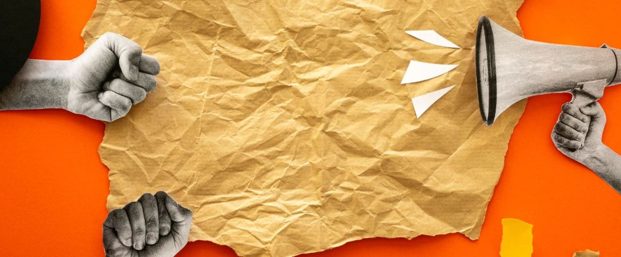 Une feuille de papier froissée posée sur une table orange avec un mégaphone
