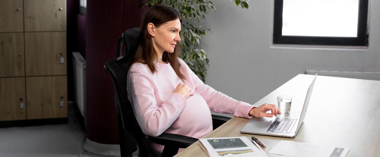 Une jeune femme enceinte assise à un bureau