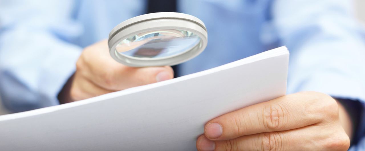 Un homme regardant une feuille avec une loupe