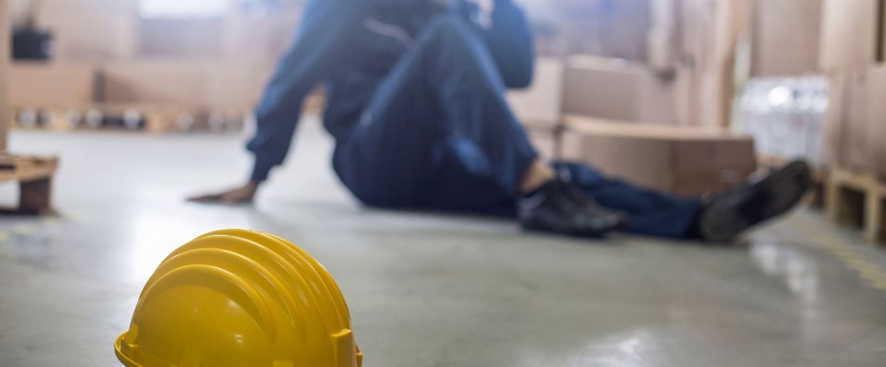 Un casque de chantier jeune posé au sol avec un homme assis derrière