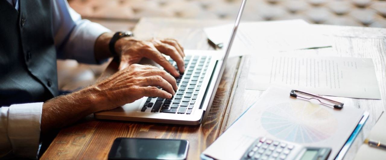 Un homme écrivant sur le clavier d'un ordinateur portable sur un bureau