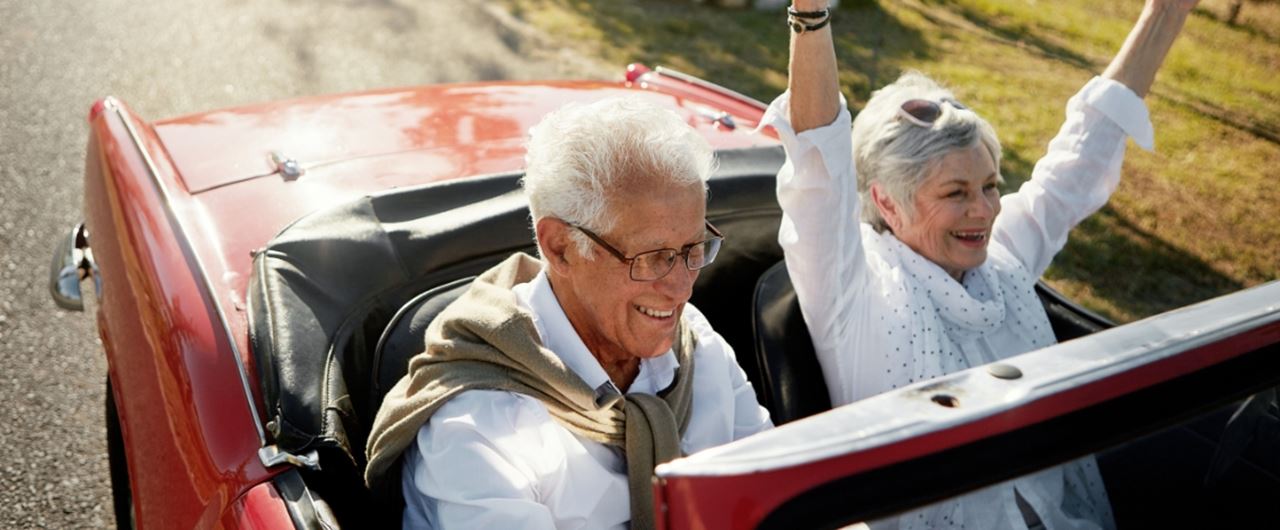 Deux personnes âgées souriant dans une voiture