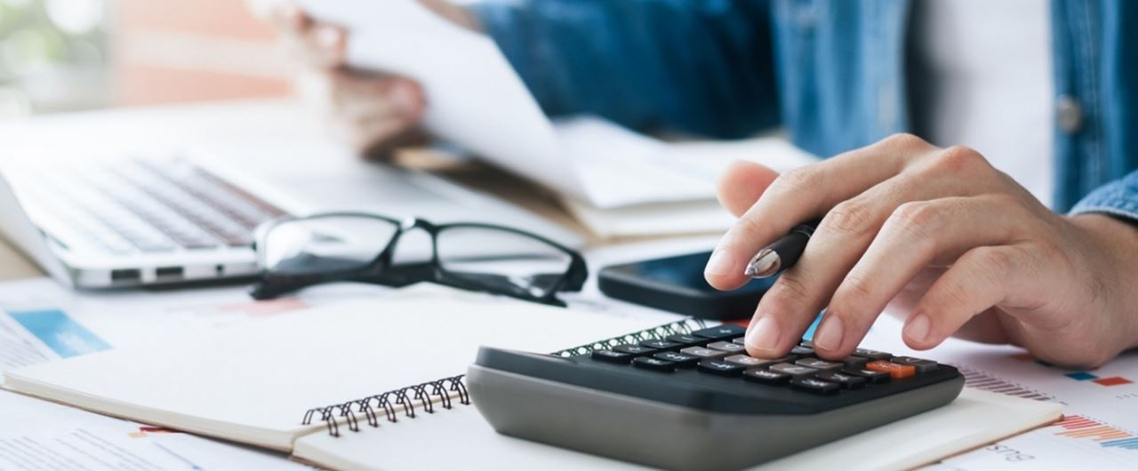Un homme avec une calculatrice, des lunettes et un cahier