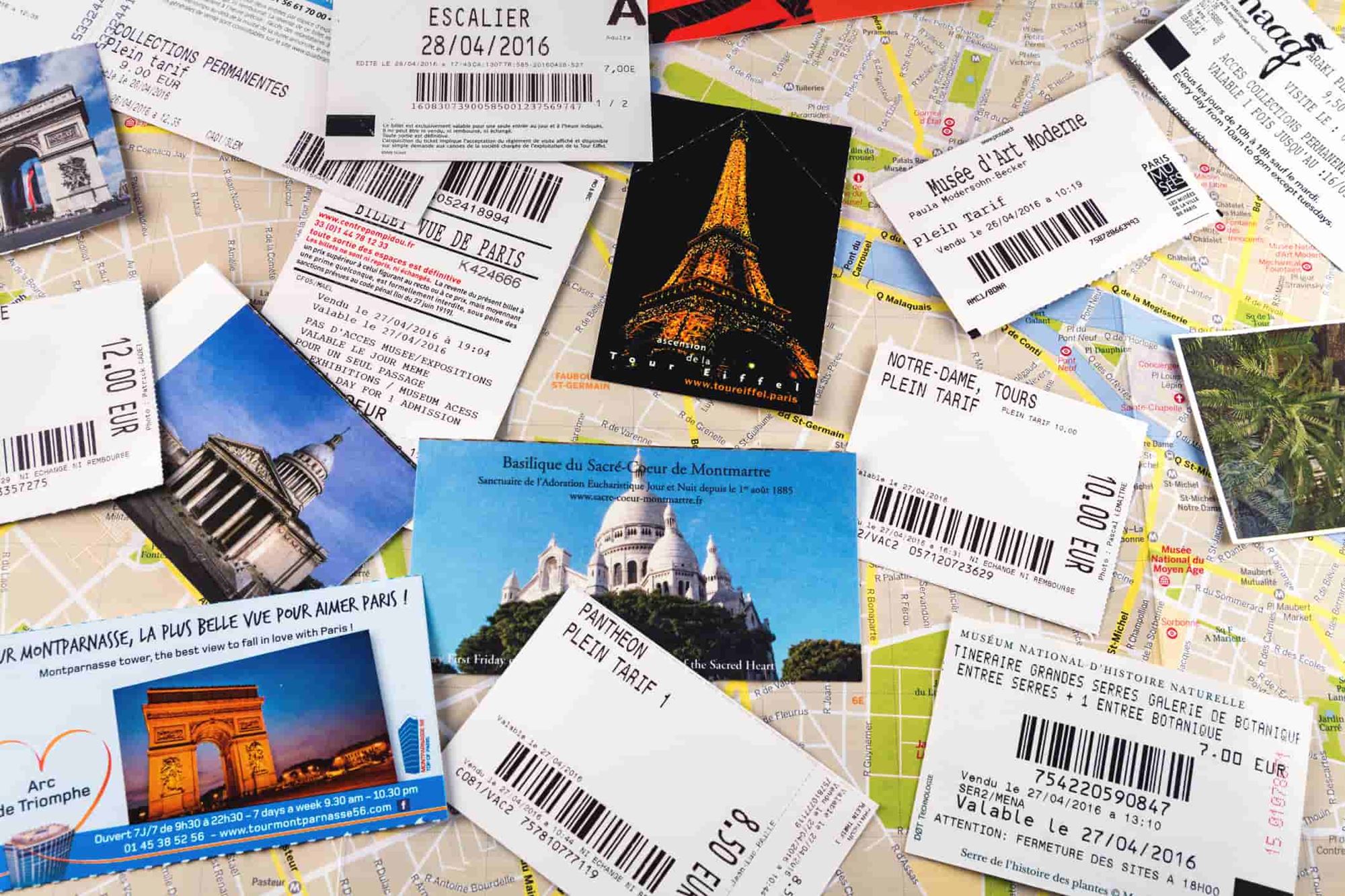 Plusieurs billets d'entrée étalés sur une table avec des photos de monuments parisiens