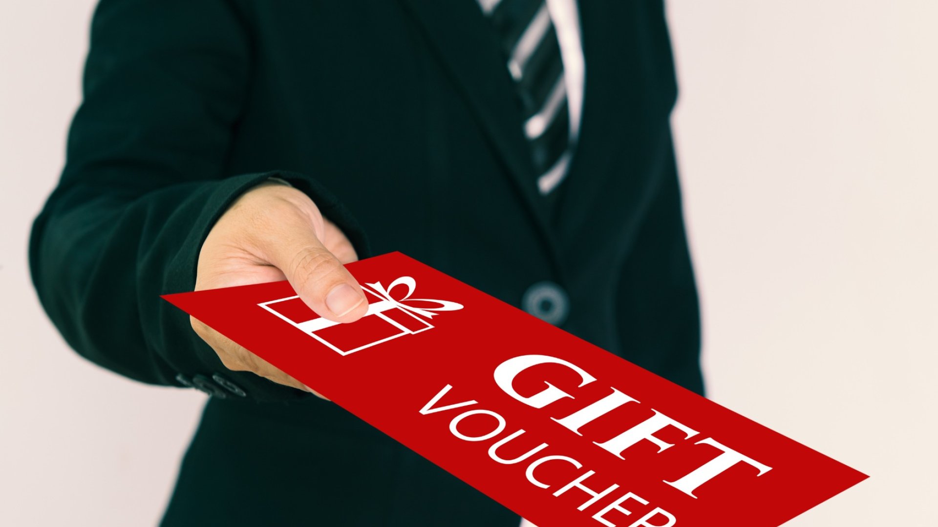Un homme tendant une enveloppe avec écrit GIFT