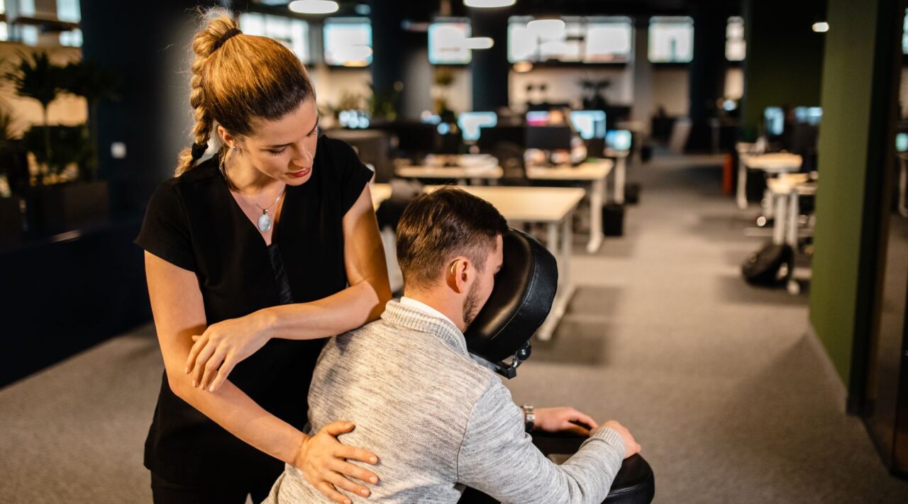 Une femme massant le dos d'un homme dans un bureau