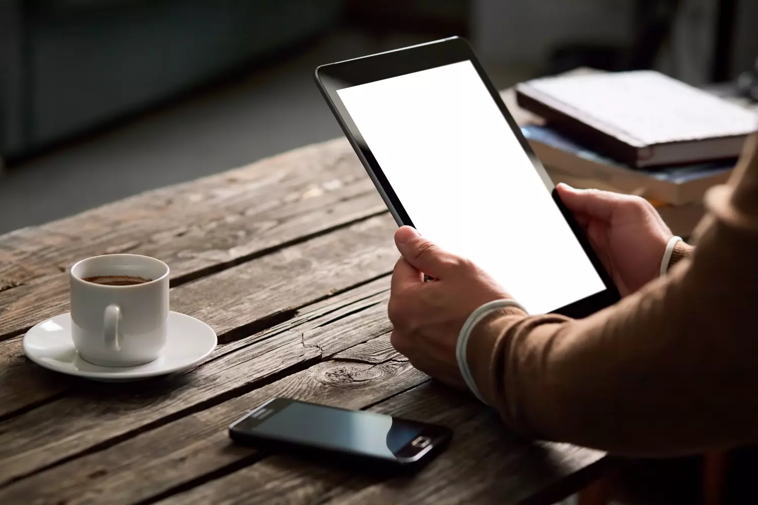 Une femme tenant une tablette avec un café à côté