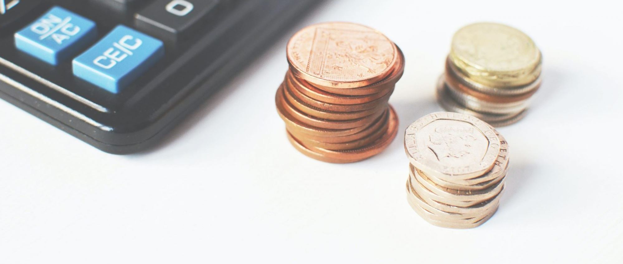 Des pièces de monnaies empilées à côté d'une calculatrice