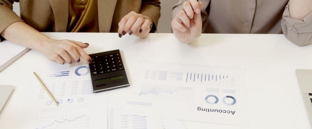 Deux femmes face à plusieurs feuilles de statistiques et utilisant une calculatrice