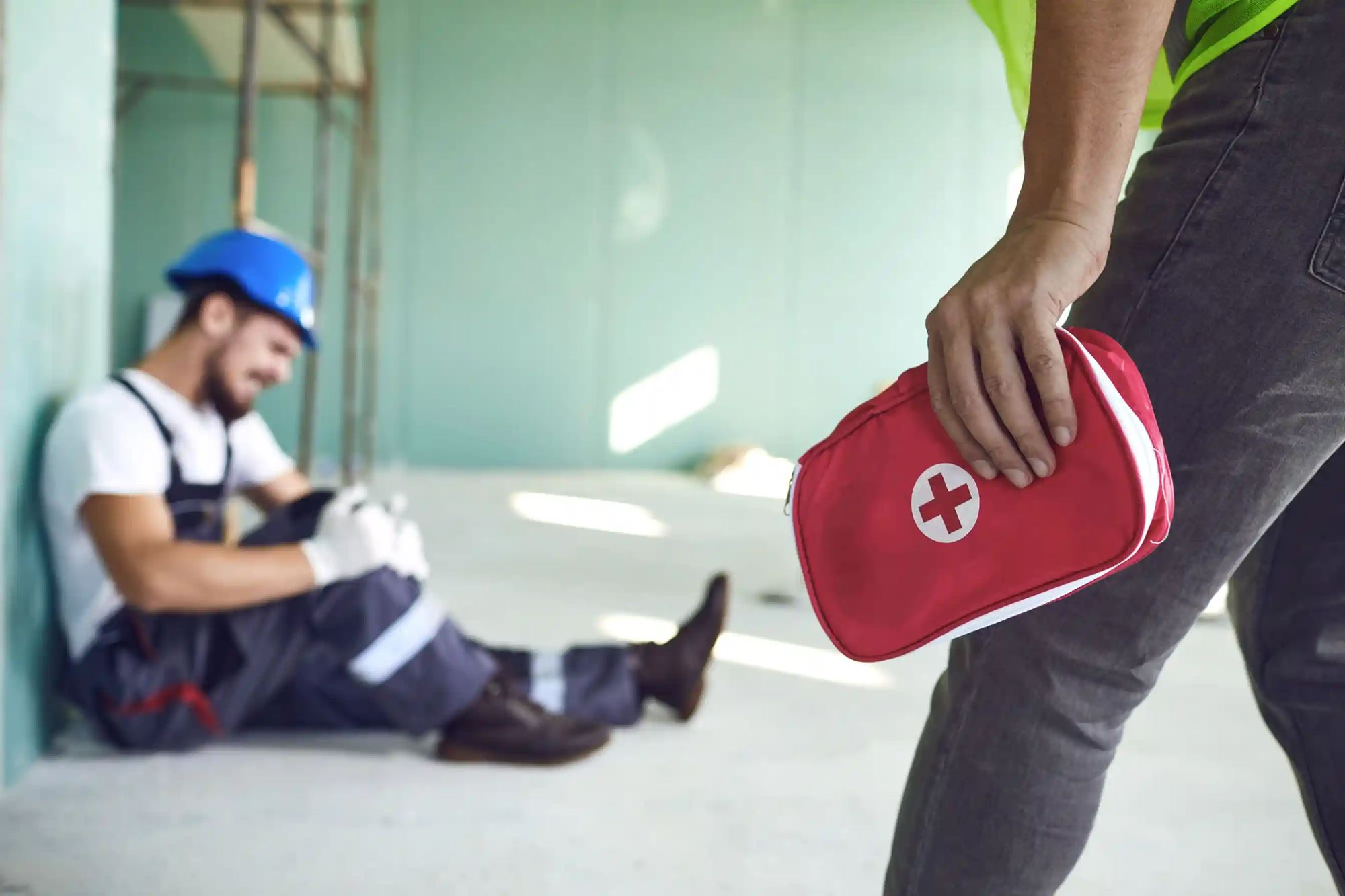 Un ouvrier apportant une trousse de secours à un ouvrier blessé