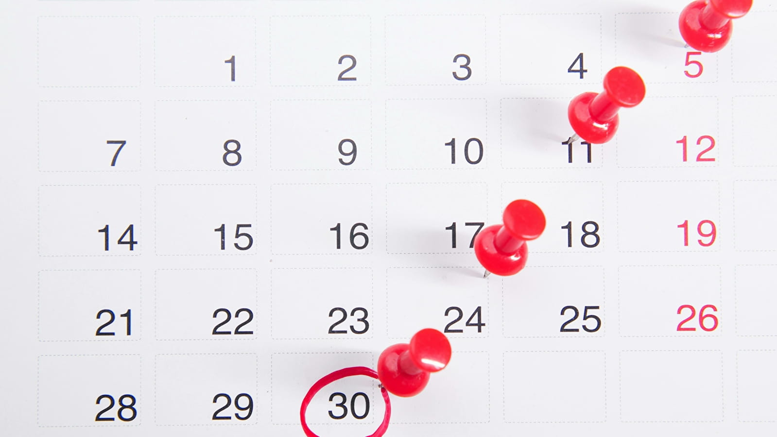 Un calendrier avec des punaises accrochées dessus