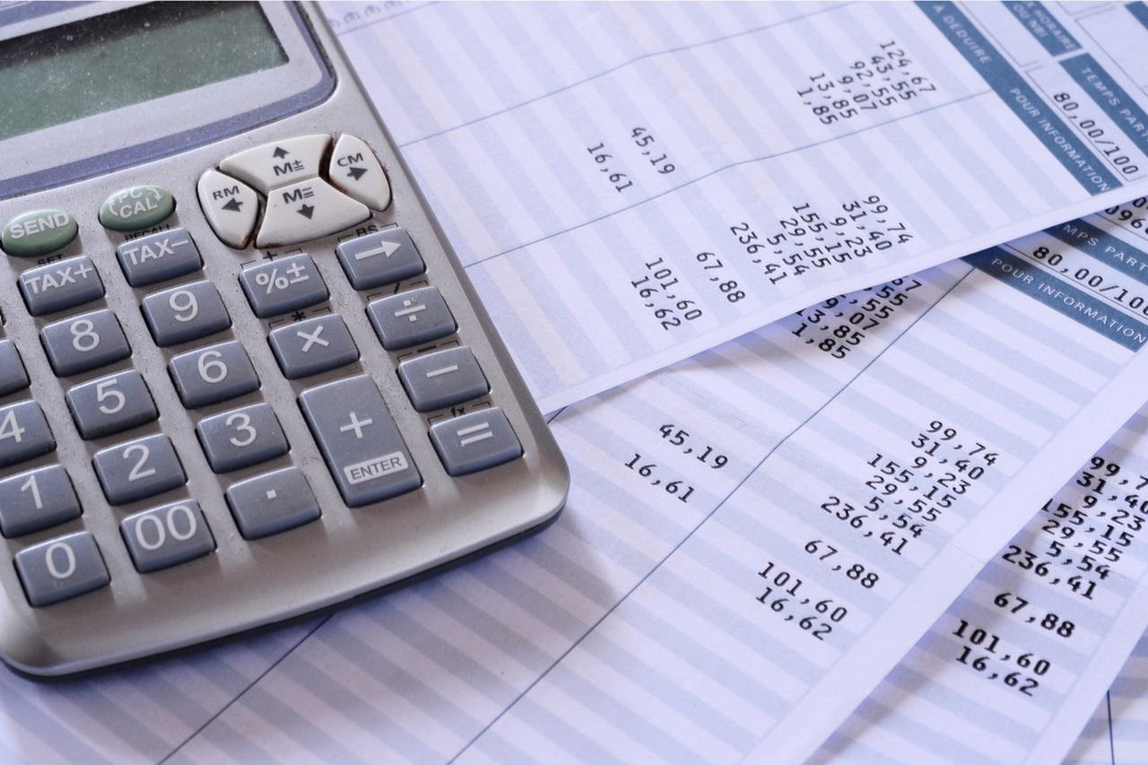 Un calculatrice à côté d'une feuille de salaire