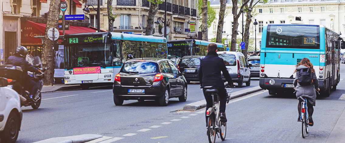 Rue parisienne avec des bus, des voitures et des vélos