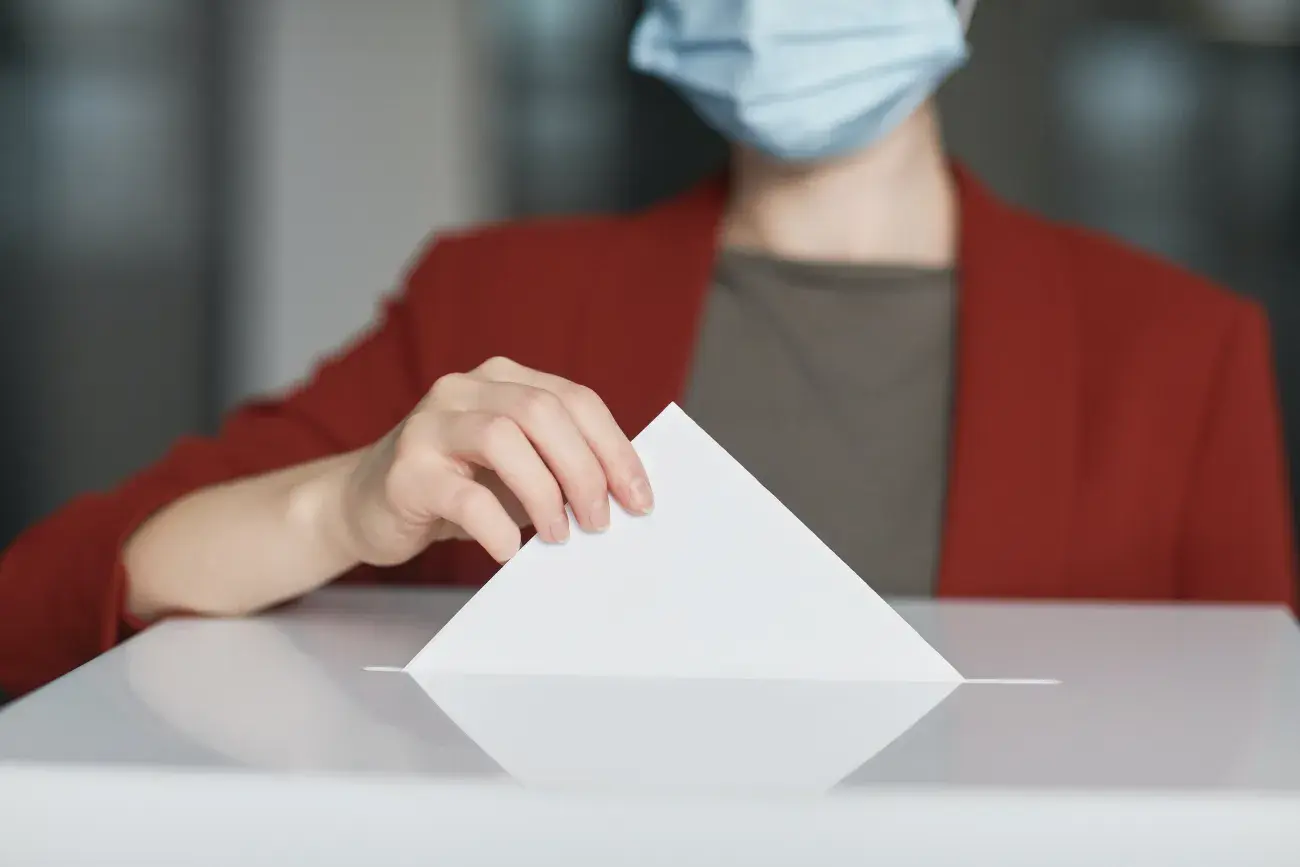 Une femme avec un masque médical en train de voter