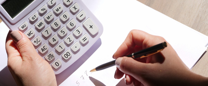 Une personne tenant une calculatrice dans la main gauche et un stylo dans la main droite