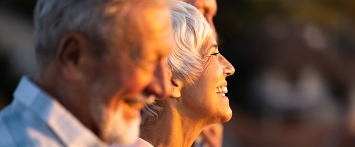 Personnes âgées souriant face au coucher de soleil