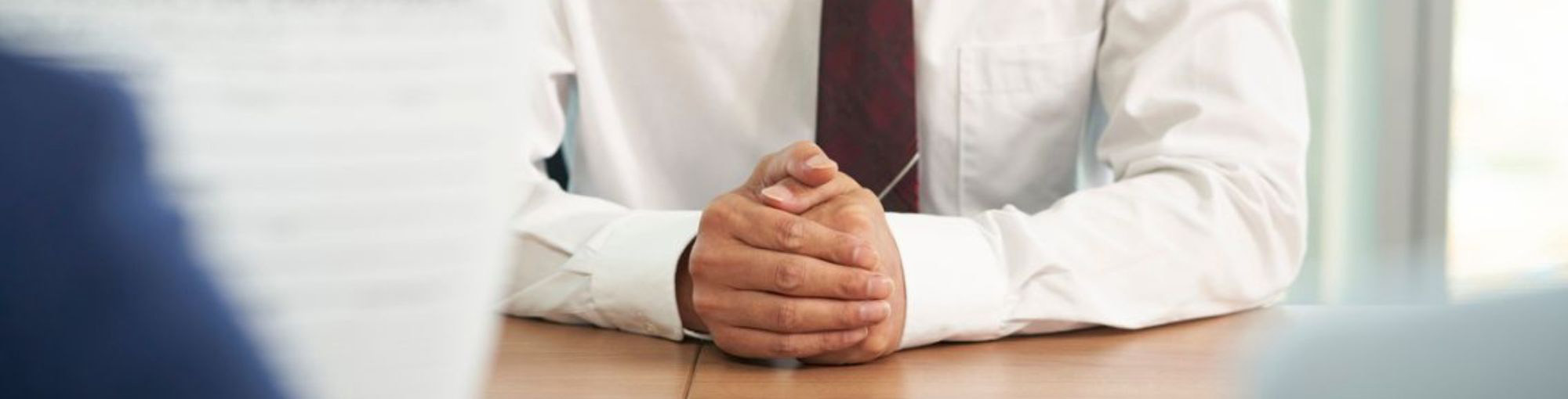 Un homme croisant les mains sur une table