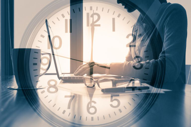 Une horloge et un homme devant un ordinateur