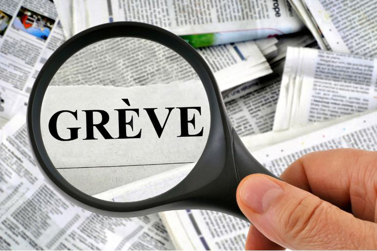 Une loupe à travers laquelle grossit le mot Grève