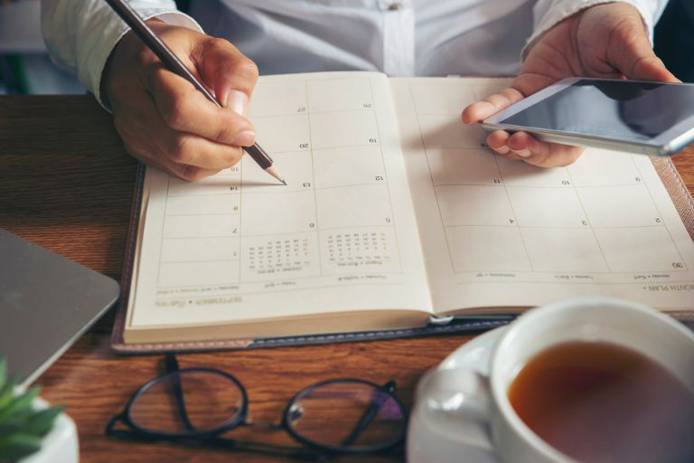 Un homme écrivant dans un agenda papier