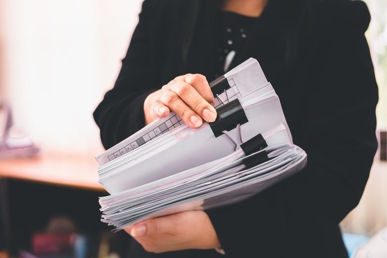 Une personne tenant plusieurs dossiers papier