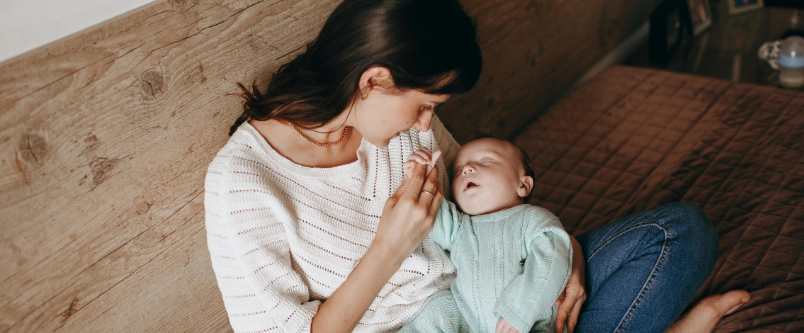 Une femme assises sur un canapé et tenant un bébé dans ses bras