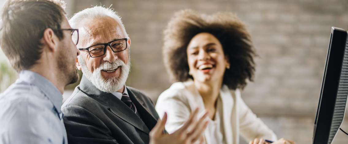 Un jeune homme, un homme âgé et une jeune femme souriant