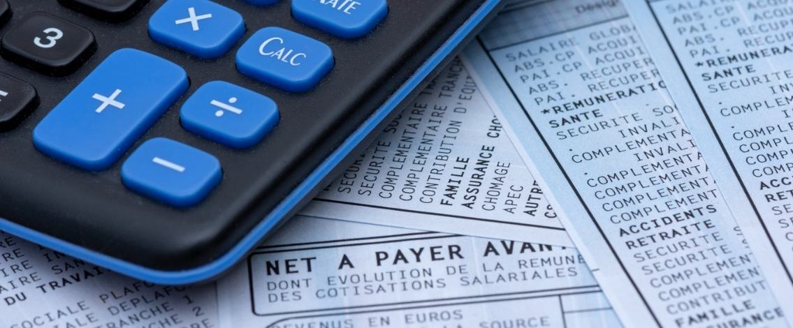 Une calculatrice posée sur plusieurs fiches de paye