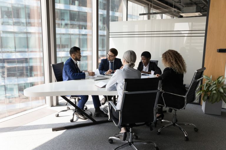 Plusieurs personnes autour d'une table ronde devant des baies vitrées