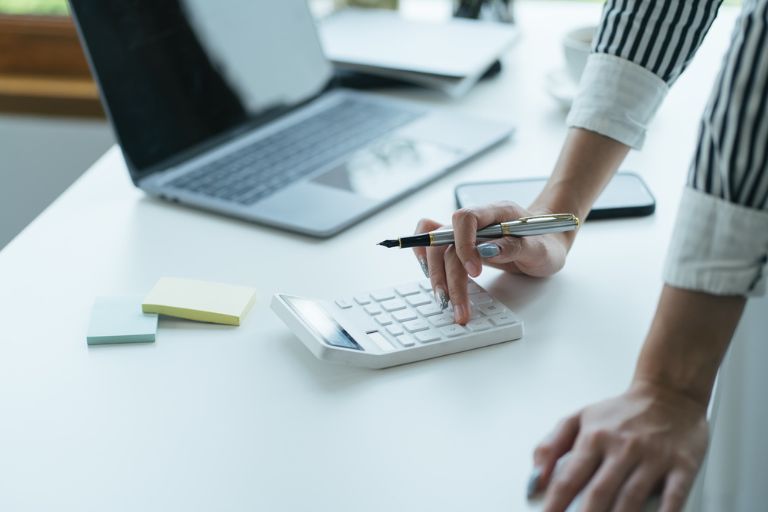Une personne debout utilise une calculatrice