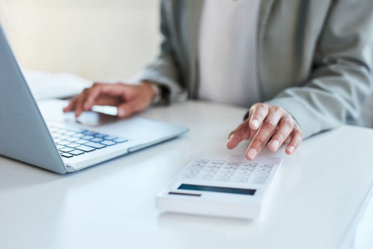 Un employé travaille sur ordinateur avec une calculatrice