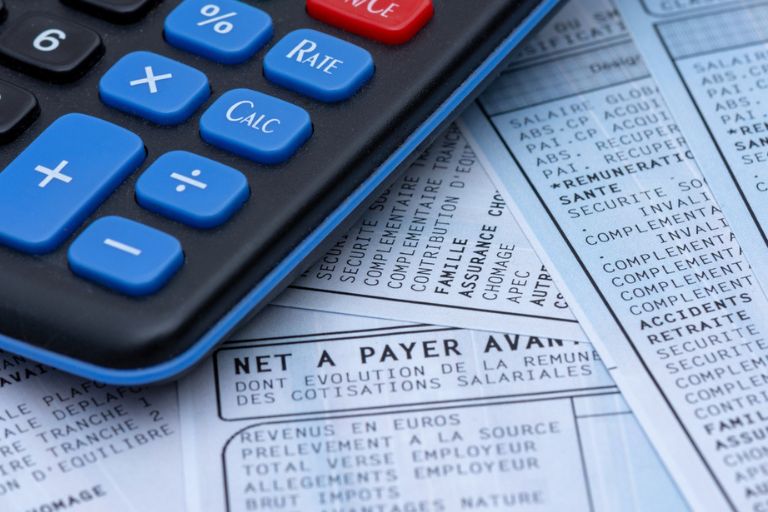 Gros plan sur une calculatrice et un bulletin de paie