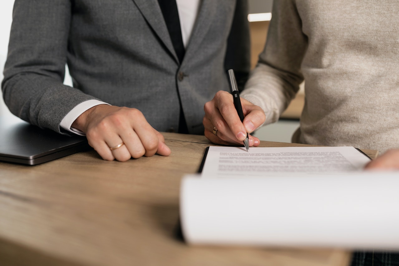 Une personne signant un contrat devant une deuxième personne