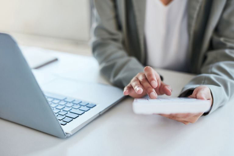 Une personne remplissant une feuille de paie avec un ordinateur et une calculatrice