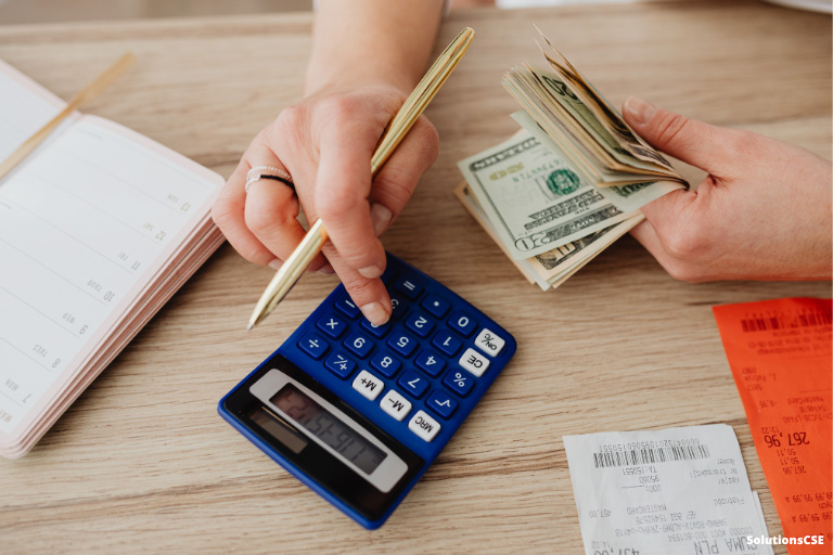 Une personne comptant des billets avec une calculatrice