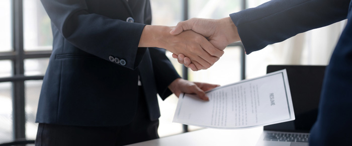 Deux personnes se serrant la main avec un contrat en main