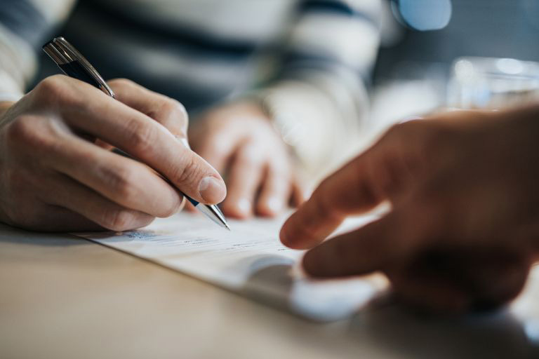 Une main signant un document
