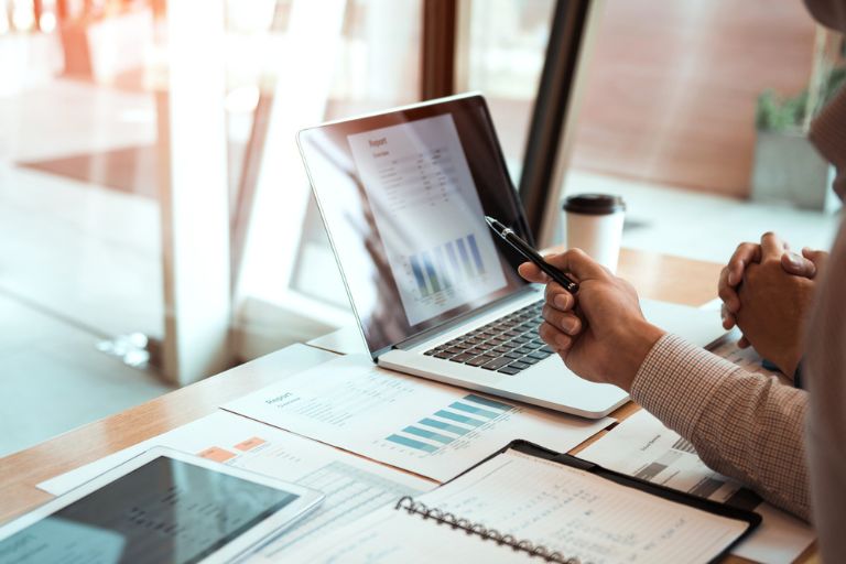Un ordinateur et une tablette posés sur une table remplie de documents