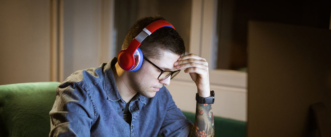 Un homme se tenant la tête avec un casque audio rouge
